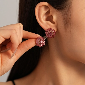 Elegant pink flower stud earrings with sparkling diamonds shown on a model's ear