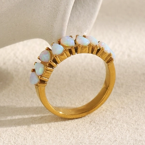 Detail of 18K gold plated ring with pear-shaped white opals on a textured stone surface