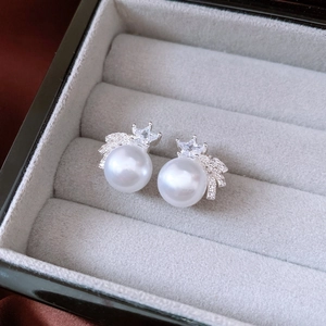 Detail of silver stud earrings with round white pearl and star-shaped zircon in jewelry box