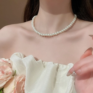 Detailed view of elegant round pearl necklace worn by model against soft background