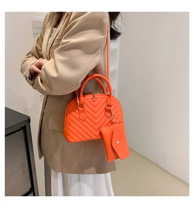 Détail du sac coquille orange vif avec matelassage en V et petit porte-monnaie assorti