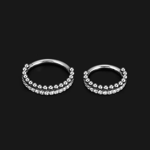 Detail von silbernen Piercingringen aus Edelstahl mit Zirkonia-Inlay und Metallperlen