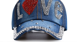 Nahaufnahme des funkelnden LOVE-Musters aus Strass auf einer blauen Denim-Baseballkappe