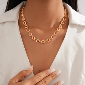 Detail of vintage gold necklace with red oval gems worn on a white shirt model