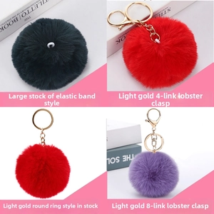 Detail of faux rabbit fur pom pom keychains with various gold metal lobster clasps and rings
