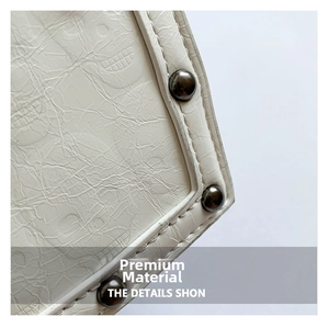 Detail of white PU leather bag featuring skull embossing and metal rivet studs