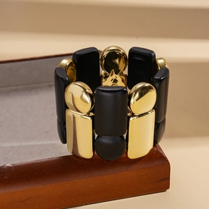 Elastic bracelet with gold rectangle and black matte round beads on wood stand