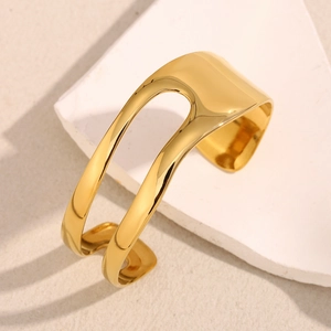 Detailed shot of an asymmetric double-layer 18K gold plated wide open bangle on stone