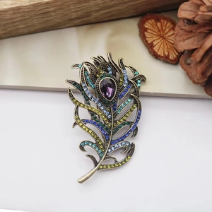 Macro shot of peacock feather brooch with purple teardrop gem and colorful rhinestones