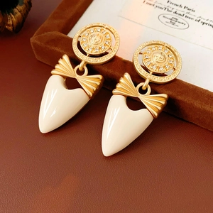 Detail of vintage bow earrings with gold textured discs and cream tapered charms