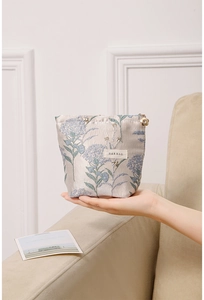 Close-up of portable makeup bag with blue hydrangea floral print and gold floral zipper