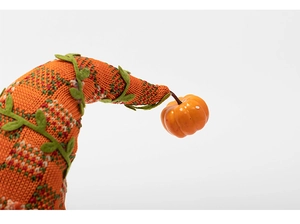 Close-up of knit pumpkin elf hat with plaid patterns and realistic vine leaf detail