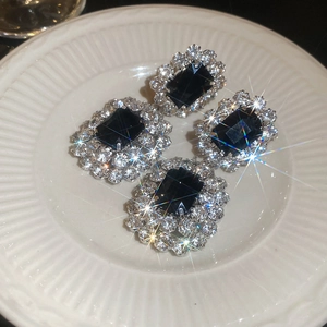 Detailansicht der ovalen Anhänger-Ohrringe mit schwarzen Kristallen und Pavé-Diamanten auf Porzellan