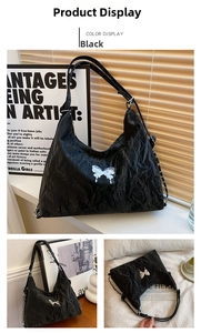 Detail of black pleated faux leather shoulder bag with silver butterfly logo buckle