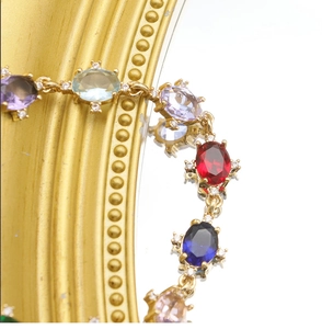 Macro shot of multi-colored oval-cut gemstones on gold bracelet with mirror reflection