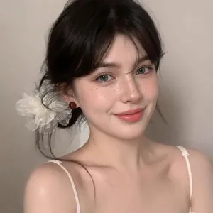 Elegant white camellia hair clip and red pearl earrings worn by a model in soft light