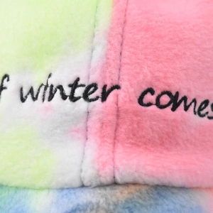 Detail of colorful tie-dye faux fur fabric and embroidered winter text on the cap