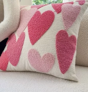 Close-up of pink tufted hearts on cream cushion cover with textured 3D embroidery detail