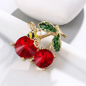 Detail of red crystal cherry brooch with gold alloy leaves and small pearl bee accent