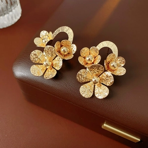 Detailed view of gold textured floral earrings on a premium leather jewelry display box