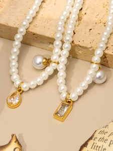 Macro detail of pearl necklaces with teardrop and rectangular crystal pendants on stone