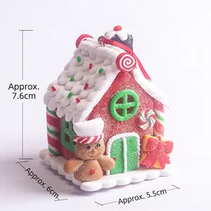 Lighted gingerbread house ornament with candy cane accents and small gingerbread man figure