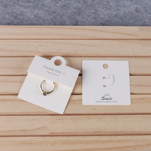 White cardboard jewelry display cards with gold ring on a minimalist wooden background