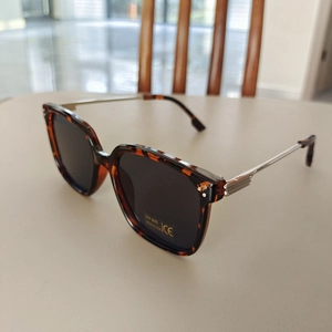 Detail view of tortoiseshell frames with UV400 lenses and metal three-dot temple accents