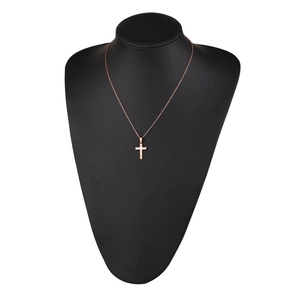 Polished rose gold cross necklace on a black mannequin display in professional lighting