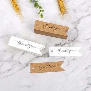 Detail of kraft paper thank you gift tags on marble surface with dried flowers