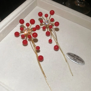 Macro detail of red floral tassel earrings with zircon center and golden chains