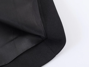 Close-up of black woven fabric texture and stitching detail on the ruffled blazer hemline