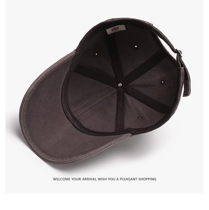 Internal view of dark brown cotton baseball cap showing black sweatband and metal buckle
