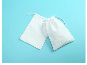Close-up of white cotton drawstring gift bags showing fabric texture on blue background