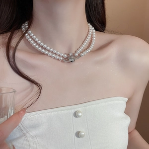 Detail of double-layer pearl necklace with silver Saturn orb pendant on a model