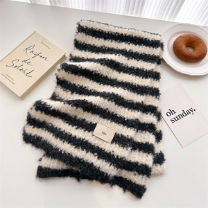 Close-up of black and white striped knit scarf with ins woven label on a white table