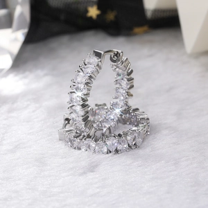 Close-up of silver hoop earrings with heart-shaped AAA zirconia on a white plush surface