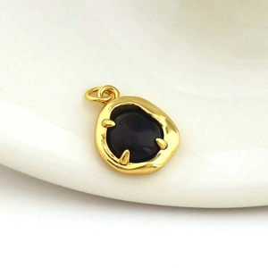 Detail of 18k gold-plated heart pendant with black agate inlay on ceramic background