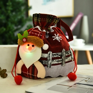 Detail of a glowing Christmas drawstring gift bag with 3D Santa Claus and red plaid fabric