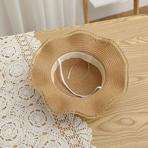 Detail of woven straw hat featuring soft wavy brim, white sweatband and elastic chin strap