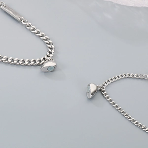 Detail of magnetic heart charms and engravable plate on stainless steel couple bracelets
