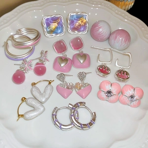 Detail shot of assorted silver and pink floral stud earrings displayed on a white plate