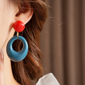 Close-up of retro geometric resin earrings in red and blue worn by a model