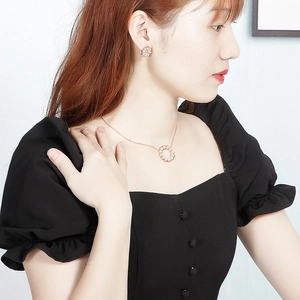 Set gioielli a fiore in oro rosa con ciondoli di perle su modella con collana e orecchini