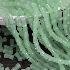 Close-up of translucent pale green bamboo-shaped beads on a dark wood background