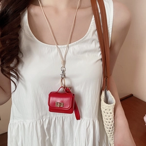 Detail of a red mini croissant leather bag pendant with white strap on white dress