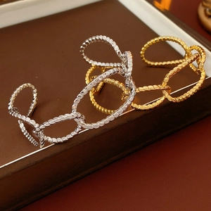 Close-up of gold and silver chunky chain link cuff bracelets on brown leather background