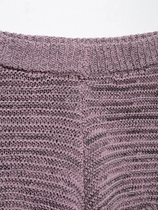 Detailed close-up of textured mauve knit fabric showing intricate hollow-out weave patterns