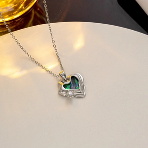 Silver necklace featuring a shell heart pendant with zircon on a textured white surface