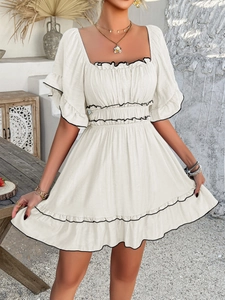 Detailed view of cream-white mini dress with black piping and ruffle hem details
